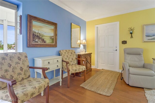 living area featuring wood-type flooring and ornamental molding