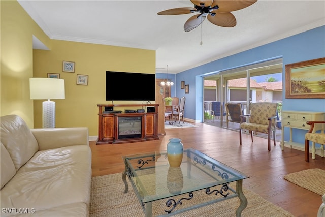 living room featuring hardwood / wood-style flooring, ceiling fan with notable chandelier, and ornamental molding