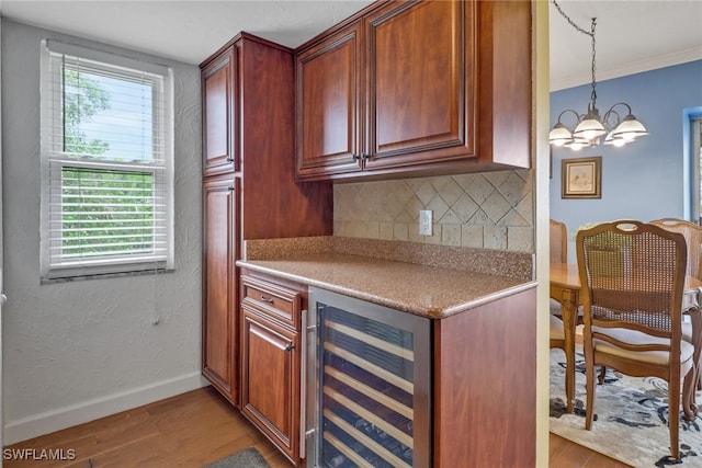 kitchen with hardwood / wood-style flooring, beverage cooler, hanging light fixtures, and decorative backsplash