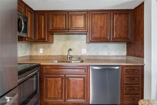 kitchen featuring stainless steel appliances, tasteful backsplash, light stone countertops, and sink