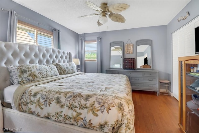 bedroom featuring ceiling fan, wood-type flooring, and a textured ceiling