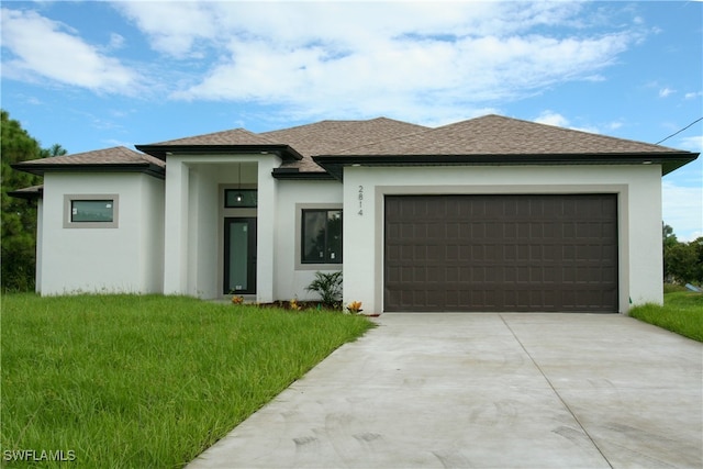 prairie-style home featuring a front yard and a garage