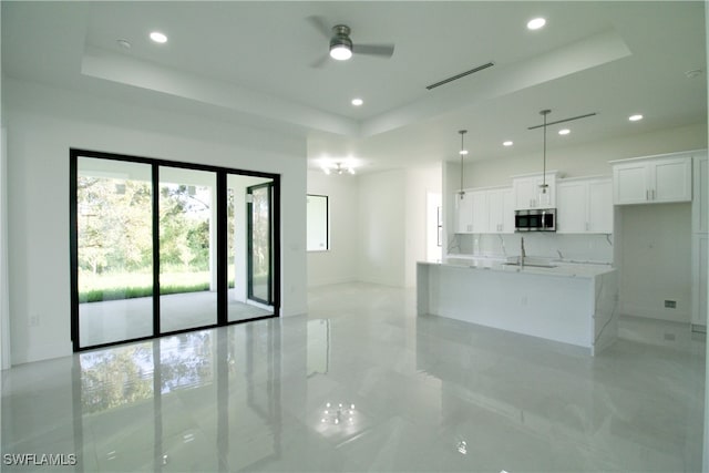 interior space with a raised ceiling, sink, and ceiling fan