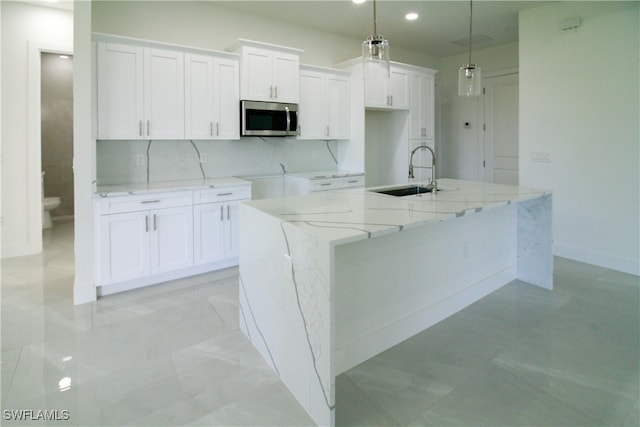 kitchen with white cabinetry, pendant lighting, and an island with sink