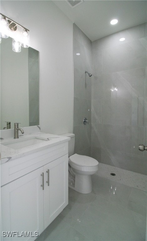 bathroom with tiled shower, vanity, and toilet