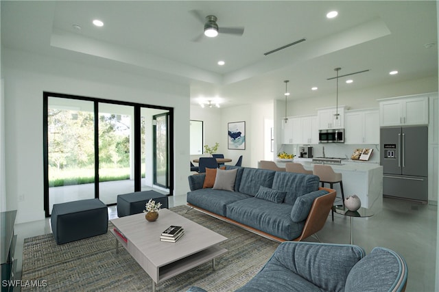 living room with ceiling fan and a raised ceiling