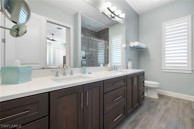 bathroom with a shower with door, wood-type flooring, toilet, and double sink vanity