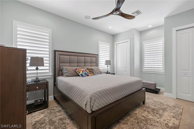 bedroom with two closets, light tile patterned floors, and ceiling fan