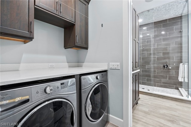 laundry area featuring light hardwood / wood-style floors, washing machine and dryer, and cabinets