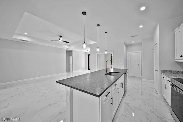 kitchen with baseboards, a tray ceiling, marble finish floor, stainless steel appliances, and a sink