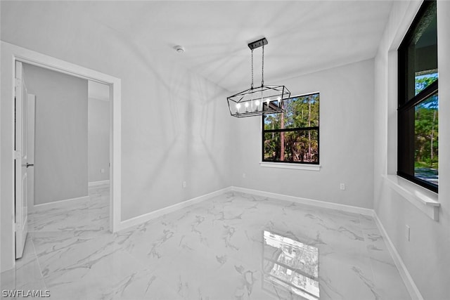 unfurnished dining area featuring baseboards, marble finish floor, and an inviting chandelier