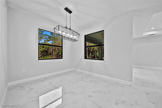 unfurnished room featuring baseboards, marble finish floor, and an inviting chandelier