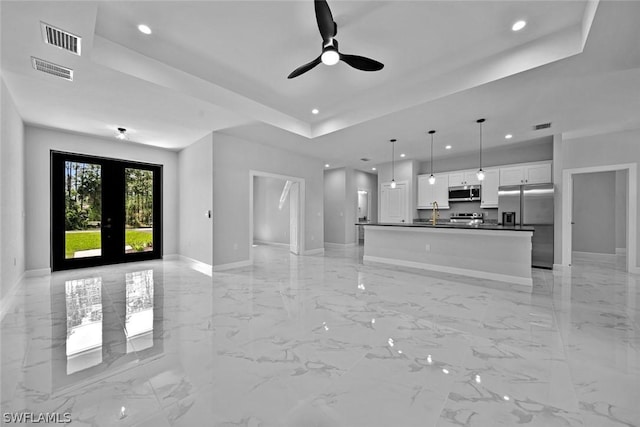 unfurnished living room with visible vents, baseboards, recessed lighting, a raised ceiling, and a ceiling fan