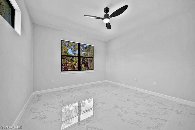 empty room with marble finish floor, baseboards, and ceiling fan