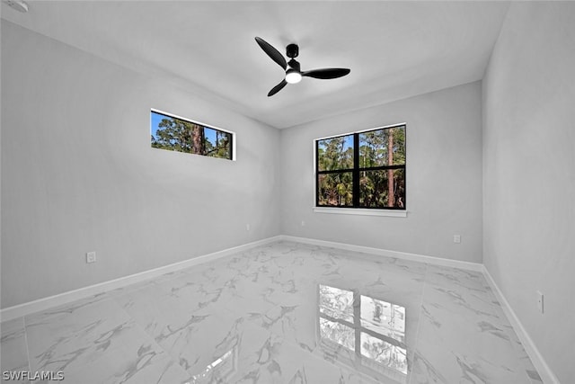 spare room featuring baseboards, marble finish floor, and a ceiling fan