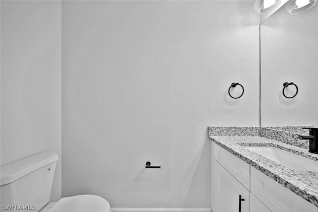 bathroom featuring vanity, toilet, and baseboards