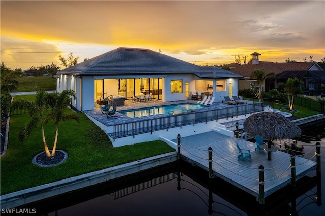 back house at dusk with a patio and a lawn