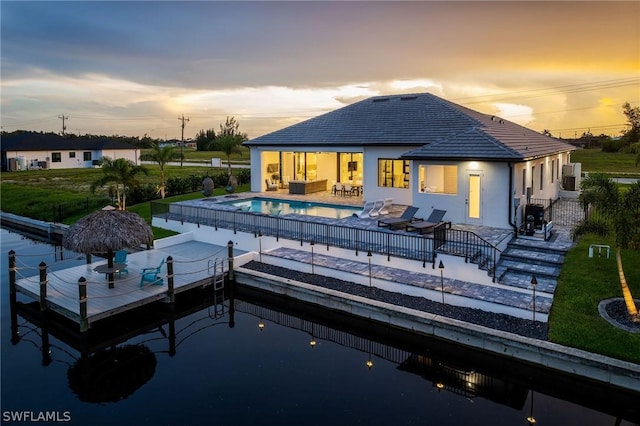 back house at dusk with an outdoor living space, a patio, and a fenced in pool