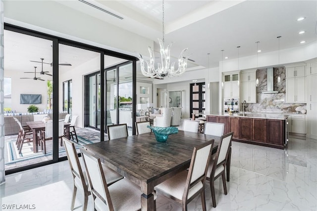 dining area featuring sink and ceiling fan with notable chandelier