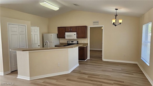 kitchen featuring pendant lighting, white appliances, an island with sink, and light hardwood / wood-style flooring