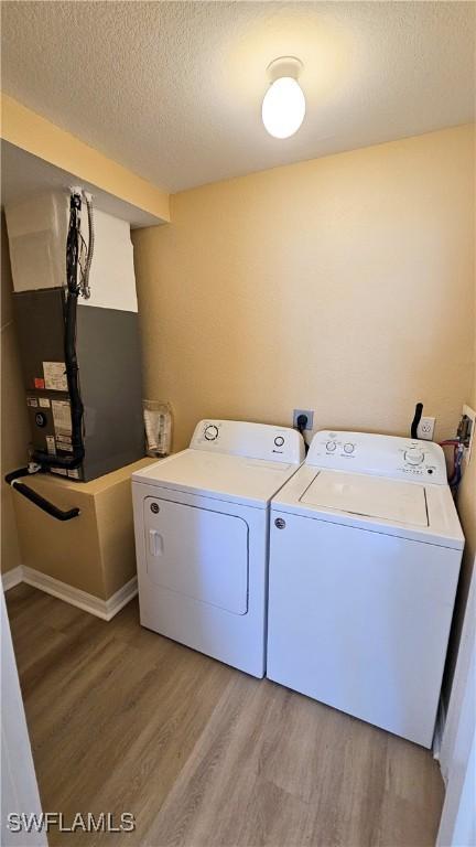 washroom featuring wood-type flooring, a textured ceiling, and independent washer and dryer