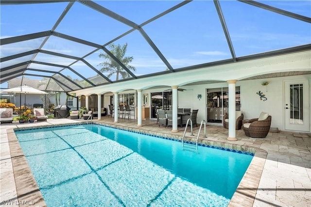 view of swimming pool featuring ceiling fan, a lanai, and a patio area