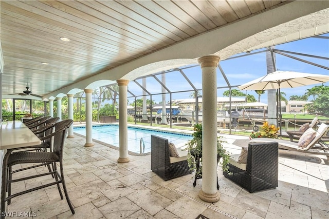 view of swimming pool featuring ceiling fan, a lanai, and a patio