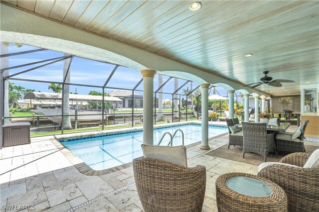 view of swimming pool with ceiling fan, a lanai, and a patio