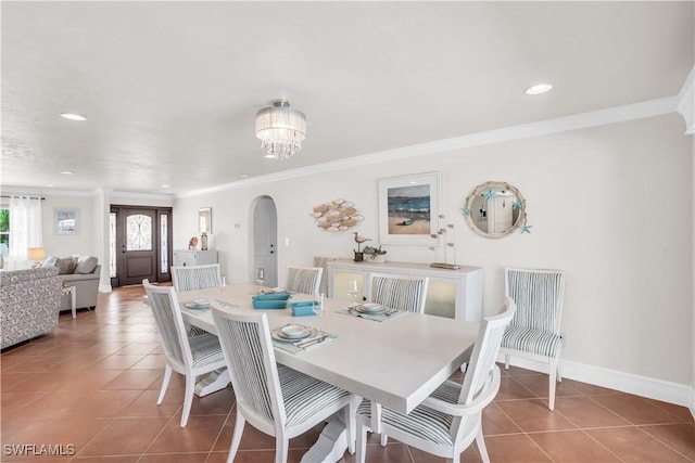 dining area with crown molding, an inviting chandelier, and tile patterned flooring