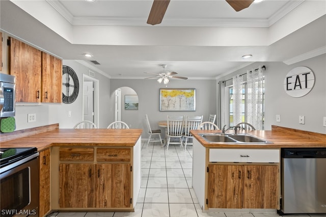 kitchen featuring ceiling fan, stainless steel appliances, a peninsula, a sink, and crown molding