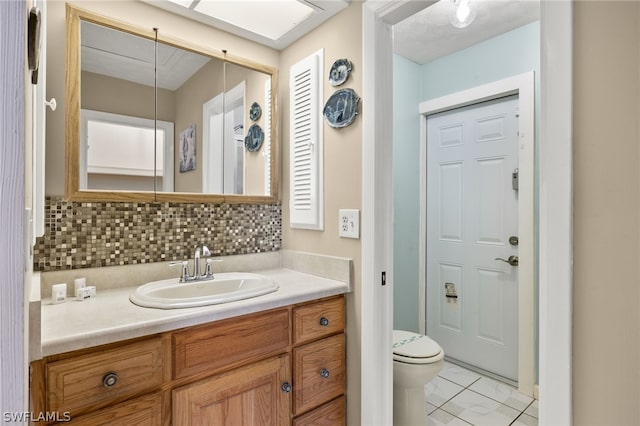 bathroom with tile patterned floors, vanity, toilet, and backsplash