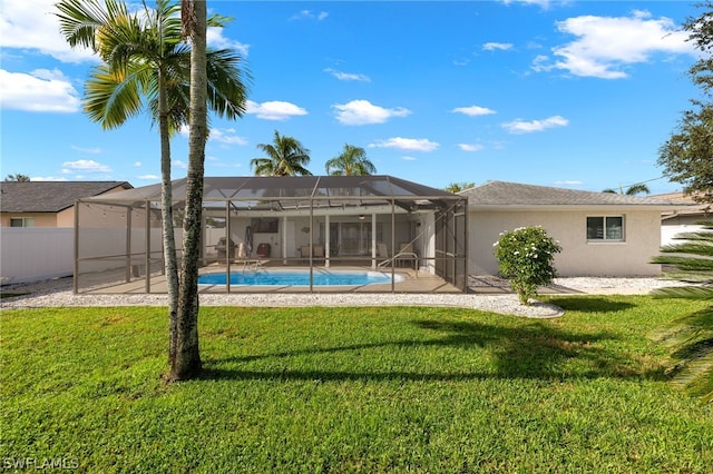 rear view of property with a lawn, a lanai, and a fenced in pool