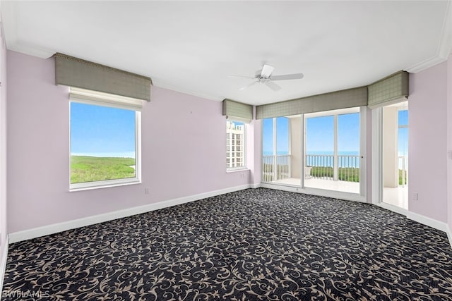 carpeted empty room featuring a ceiling fan, baseboards, and ornamental molding