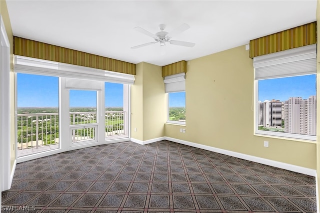 spare room with baseboards, dark colored carpet, and ceiling fan