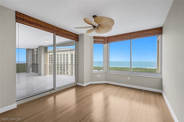 empty room featuring wood finished floors, a healthy amount of sunlight, baseboards, and ceiling fan