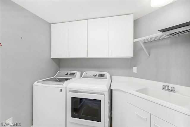 washroom with cabinet space, independent washer and dryer, and a sink