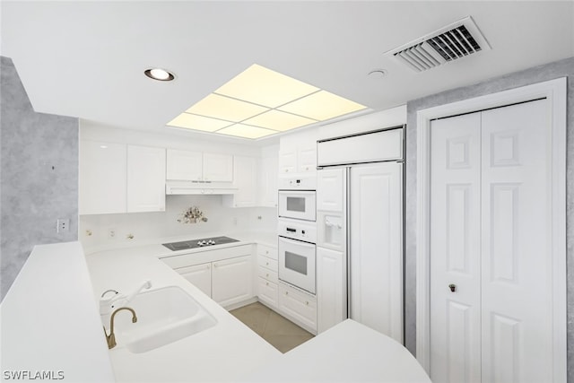 kitchen with visible vents, under cabinet range hood, a sink, paneled built in fridge, and black electric cooktop