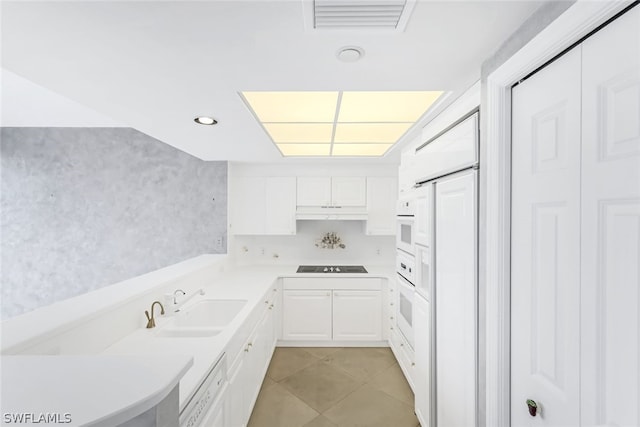 kitchen featuring under cabinet range hood, light tile patterned floors, white cabinetry, black electric cooktop, and a sink