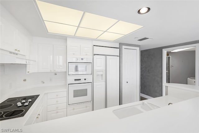 kitchen featuring paneled fridge, visible vents, under cabinet range hood, white oven, and black electric cooktop