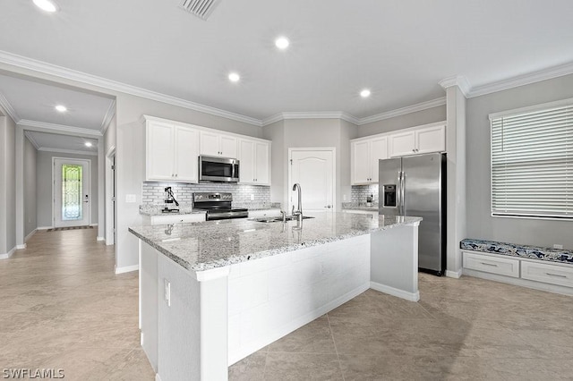 kitchen featuring sink, appliances with stainless steel finishes, a kitchen island with sink, white cabinets, and ornamental molding