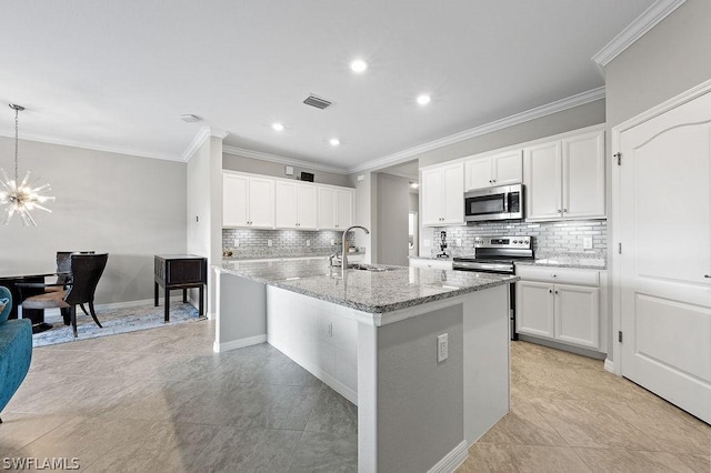 kitchen featuring crown molding, white cabinetry, a kitchen island with sink, and appliances with stainless steel finishes