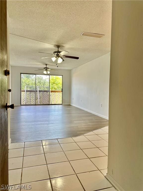 unfurnished room with ceiling fan, a textured ceiling, and light hardwood / wood-style flooring