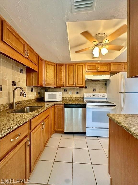 kitchen with light tile patterned floors, white appliances, a raised ceiling, and sink