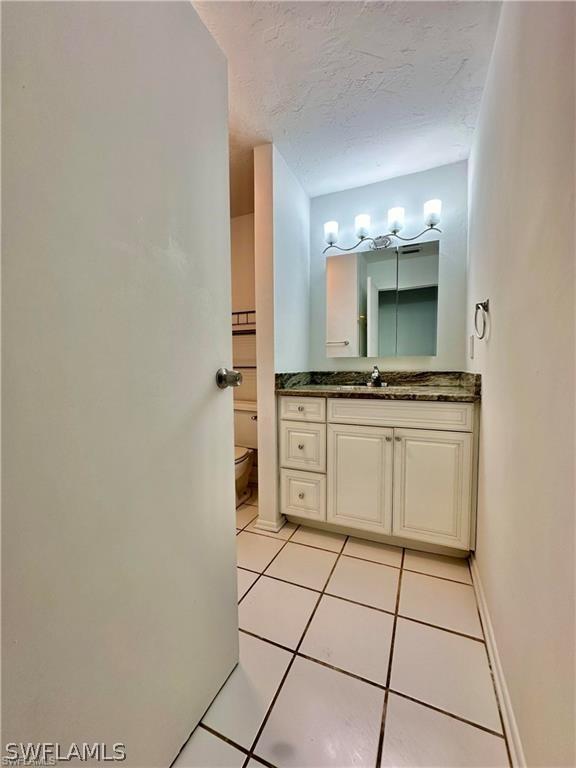 bathroom featuring tile patterned floors, vanity, toilet, and a textured ceiling