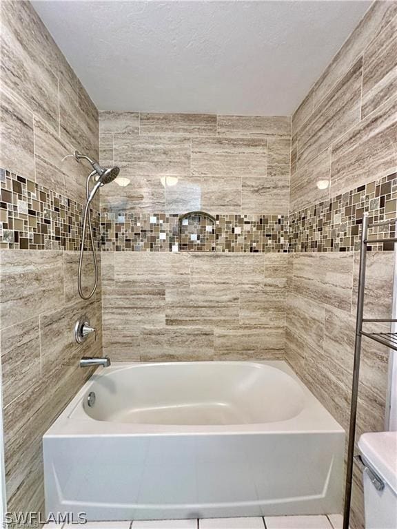 bathroom featuring tile patterned floors, tiled shower / bath combo, and toilet