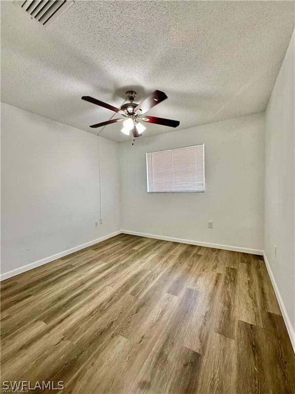 spare room with ceiling fan, wood-type flooring, and a textured ceiling