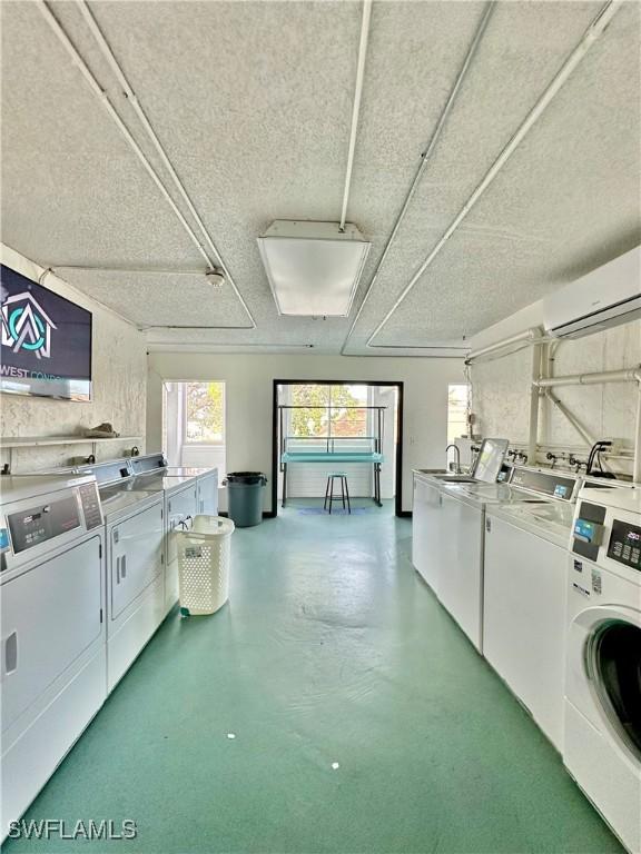 clothes washing area featuring washer and dryer, an AC wall unit, and a textured ceiling