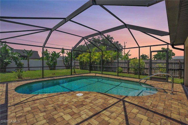 pool at dusk featuring a patio and glass enclosure