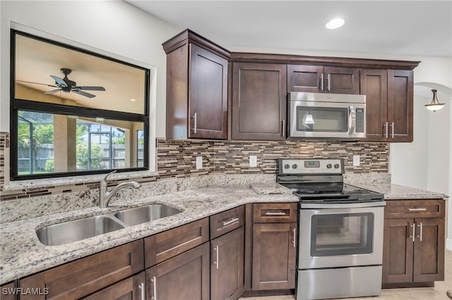 kitchen with appliances with stainless steel finishes, sink, and light stone counters