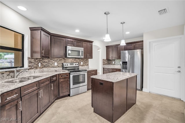 kitchen with sink, appliances with stainless steel finishes, hanging light fixtures, dark brown cabinetry, and a kitchen island